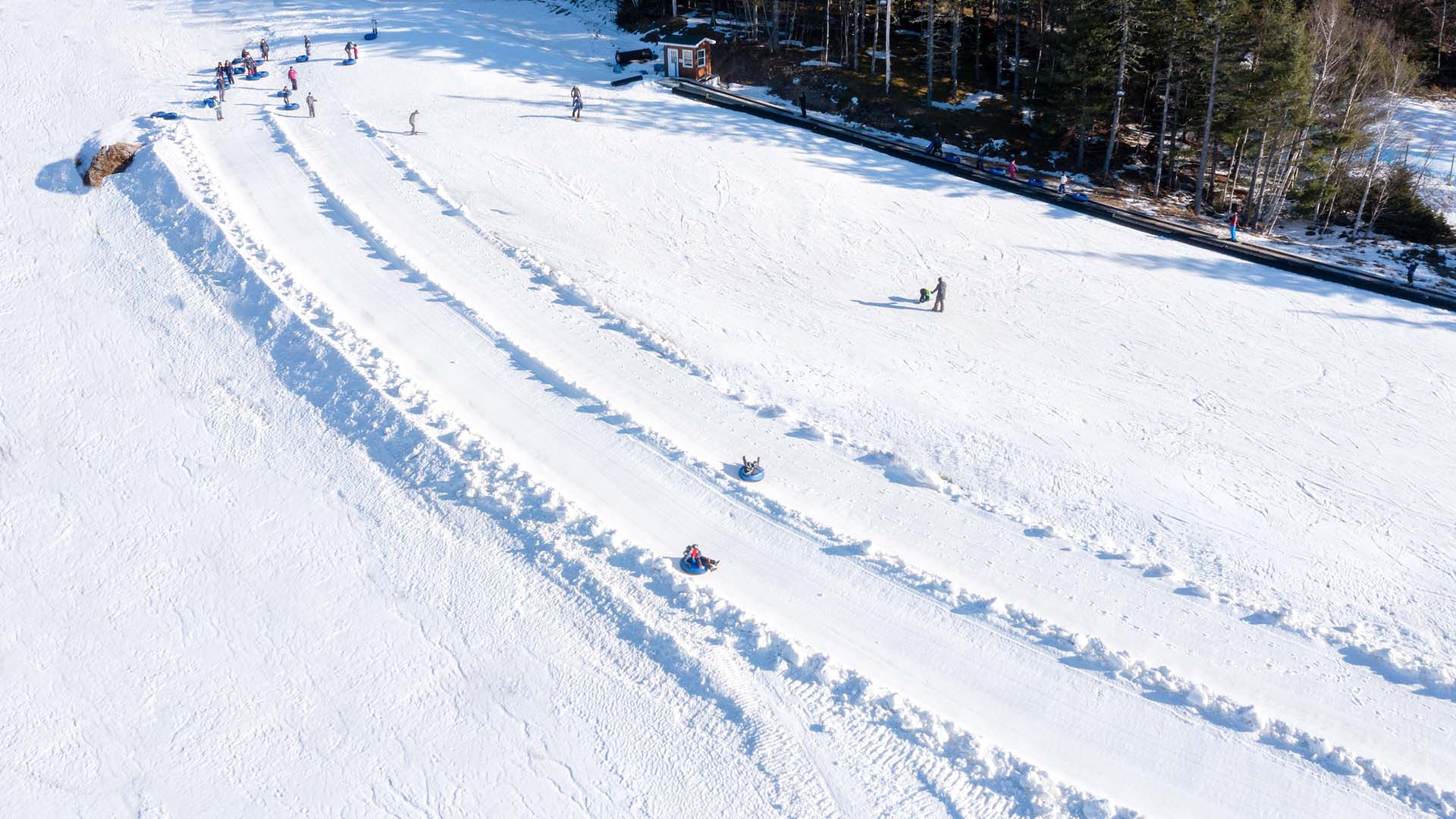 A winter scene at Ben Eoin ski resort in Nova Scotia Canada featuring a skier in action a ski lift in the background and a snowmobile partially visible.