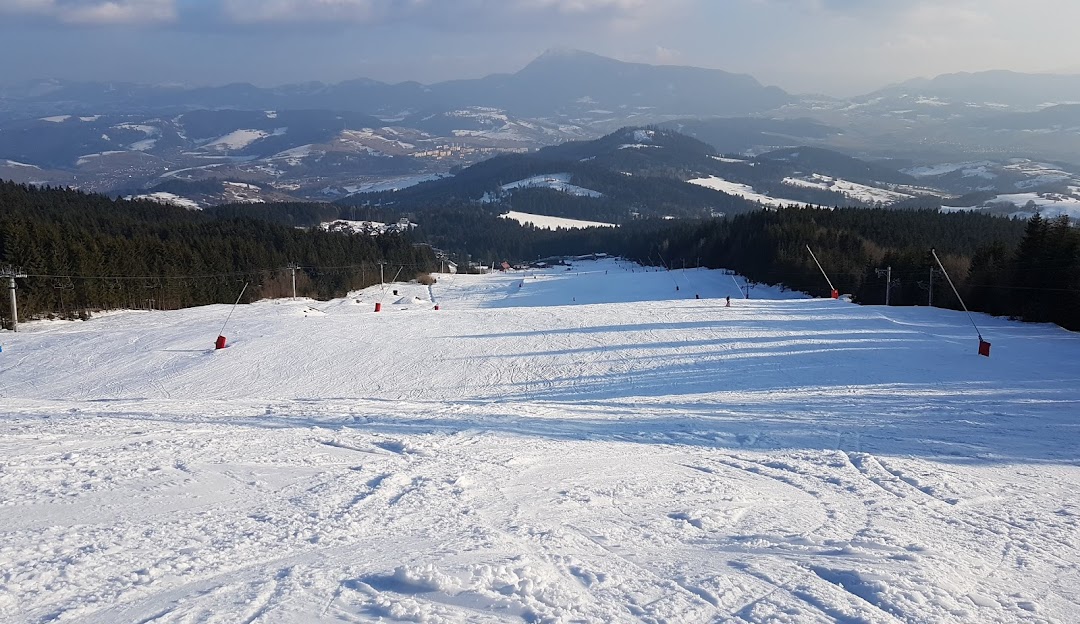 Winter scene at Kubínska hoľa ski resort, Slovakia. Skiers enjoying the snowy slopes, with a charming chalet nestled amidst the white landscape.