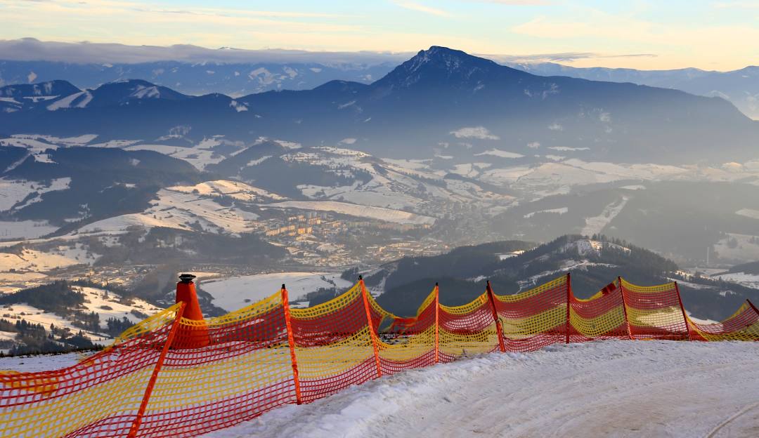 Winter scene at a ski resort in Kubínska hoľa, Slovakia, capturing a skier gliding down snow-covered slopes amidst breathtaking mountain scenery, with a charming chalet in view.
