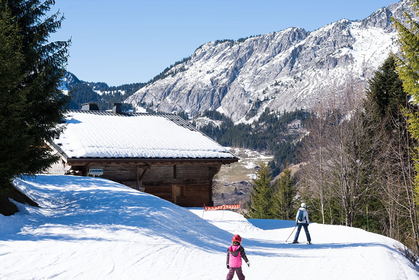 A winter sports scene at Chapelle d'Abondance in France featuring a bustling ski resort with a chalet and a family enjoying skiing.