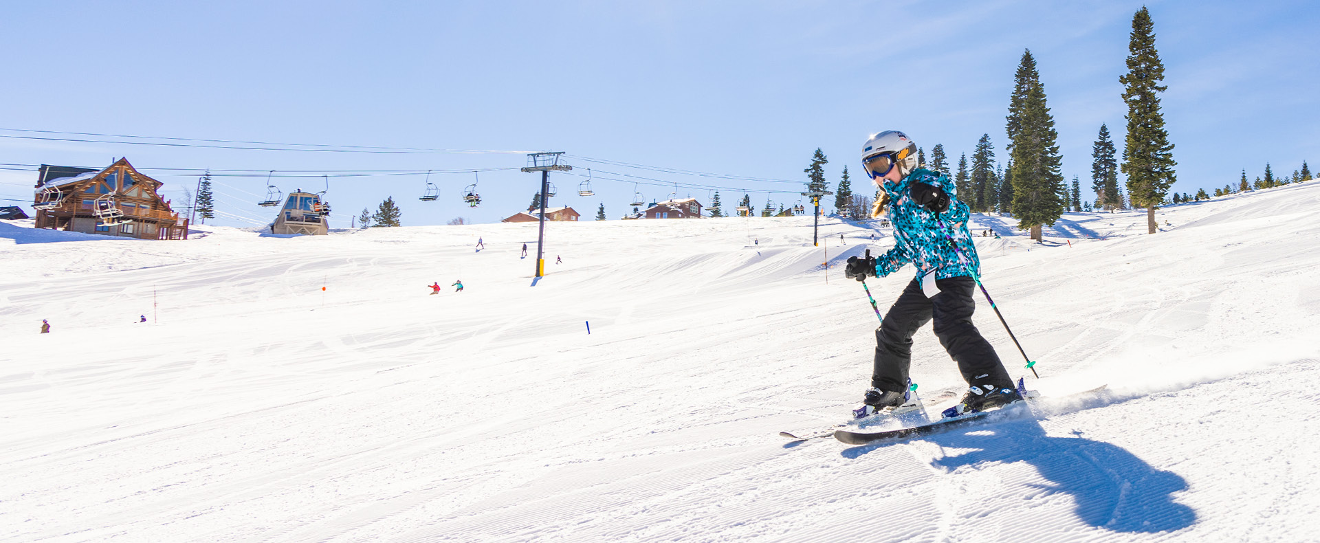 A skier and snowboarder making their way down a snowy slope at the Tahoe Donner ski resort in Lake Tahoe Truckee California with a ski lift in the background.