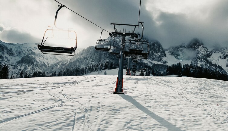 A chalet and ski lift in the picturesque Zahmer Kaiser ski resort in Tyrol Austria. Winter sports enthusiasts can be seen with a skier in the foreground enjoying this winter wonderland.