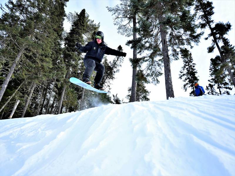 A snowboarder gliding down the snowy slopes at Pin Rouge in New Richmond Quebec immersed in a captivating winter landscape covered in a fresh blanket of snow.