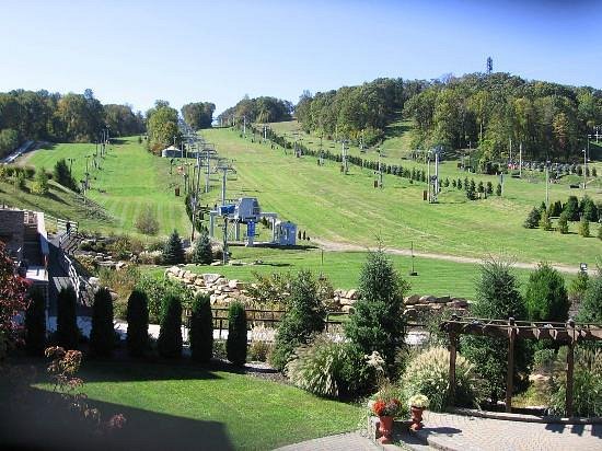 Image of Bear Creek Mountain Resort in Pennsylvania, featuring a charming chalet nestled in snow, complemented by a ski lift leading to the top of frosted slopes, showcasing the essence of a lively winter sports center.