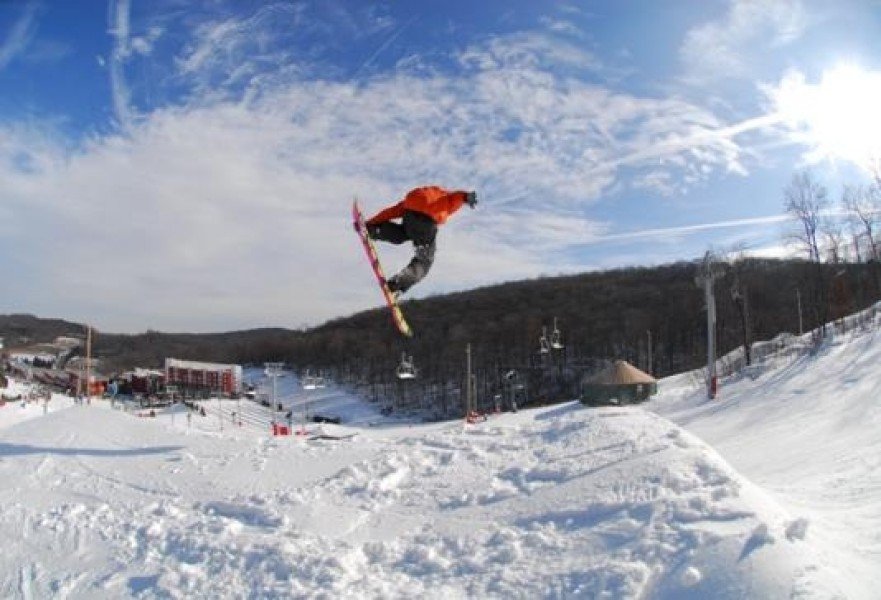 Snowboarder and skier traversing Bear Creek Mountain Resort in Macungie, Pennsylvania, offering a lively winter sports scene amidst the crisp, cold weather.