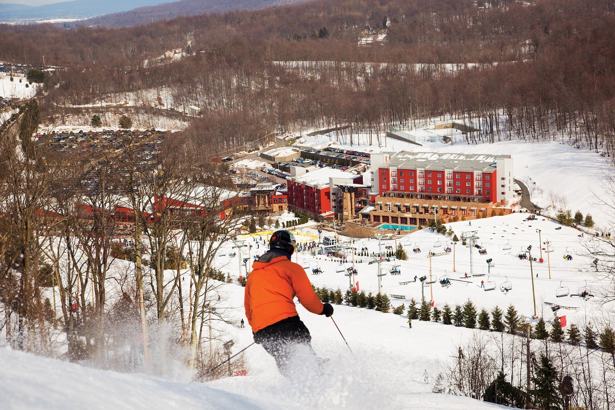 Winter sports enthusiasts enjoying a day at Bear Creek Mountain Resort in Macungie, Pennsylvania, featuring a skier descending snow-covered slopes.