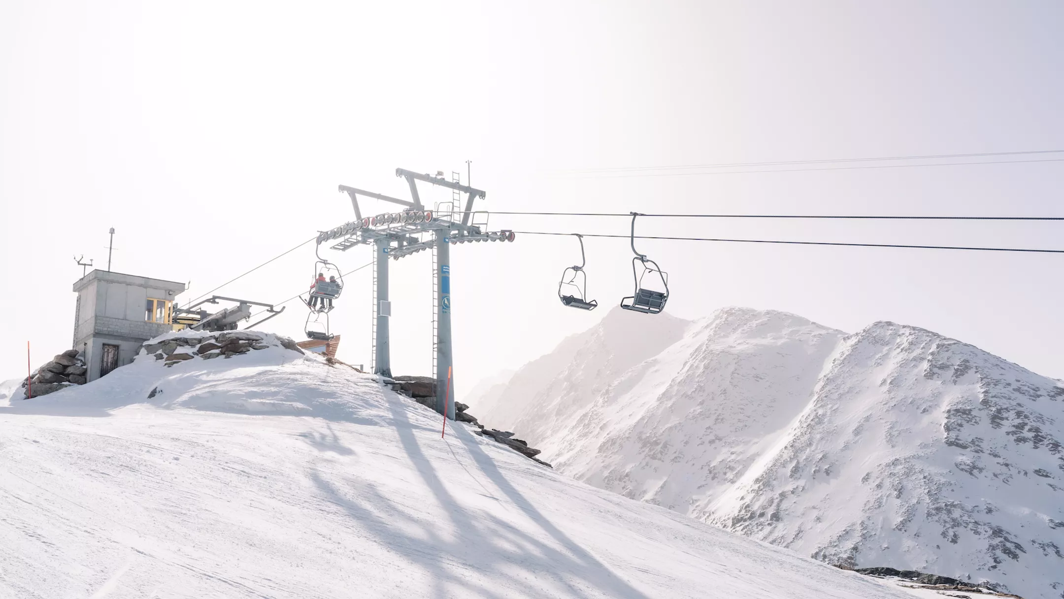 A scenic view from Heidbodme - Saas-Almagell in Switzerland featuring a prominent ski lift a sprawling ski resort backdrop a vibrant winter sports scene with a skier and a charming chalet in the peaceful snowy landscape.