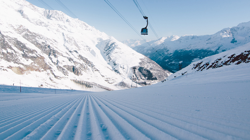 View of Saas-Almagell ski resort in Switzerland featuring a ski lift transporting a skier up the snow-covered slopes highlighting winter sport activities.