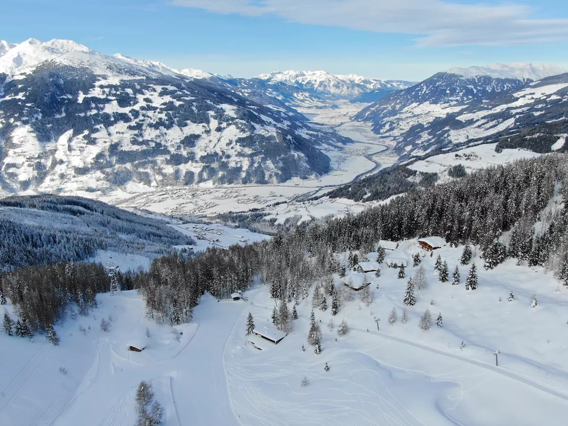 Ski resort in Gerlosstein, Austria, filled with winter sports enthusiasts. A cozy chalet in the backdrop of stunning winter scenery, covered in a blanket of snow.