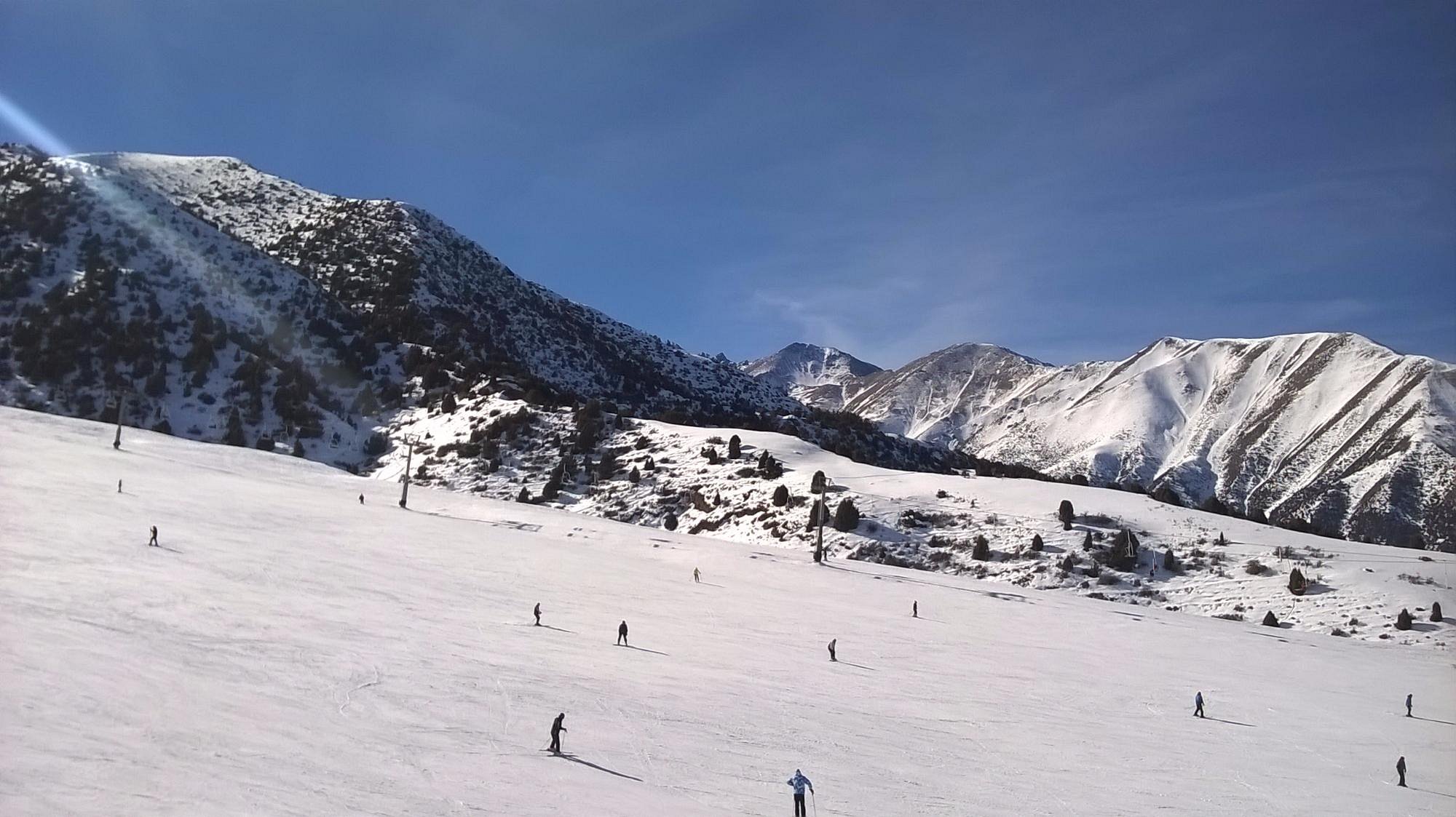 Winter sports scene at Chunkurchak Ski Resort in Kyrgyzstan, featuring a chalet, ski slopes, and stunning snow-covered scenery.