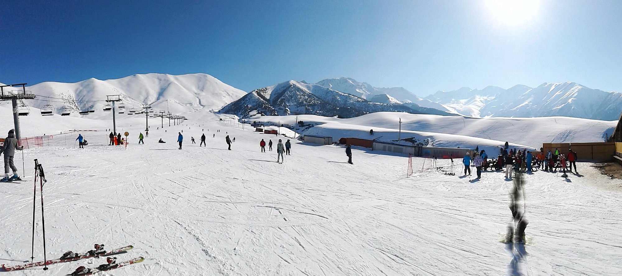 A stunning winter scene at the Chunkurchak ski resort in Kyrgyzstan, featuring a chalet amidst the snowy landscape, buzzing with winter sports activities.