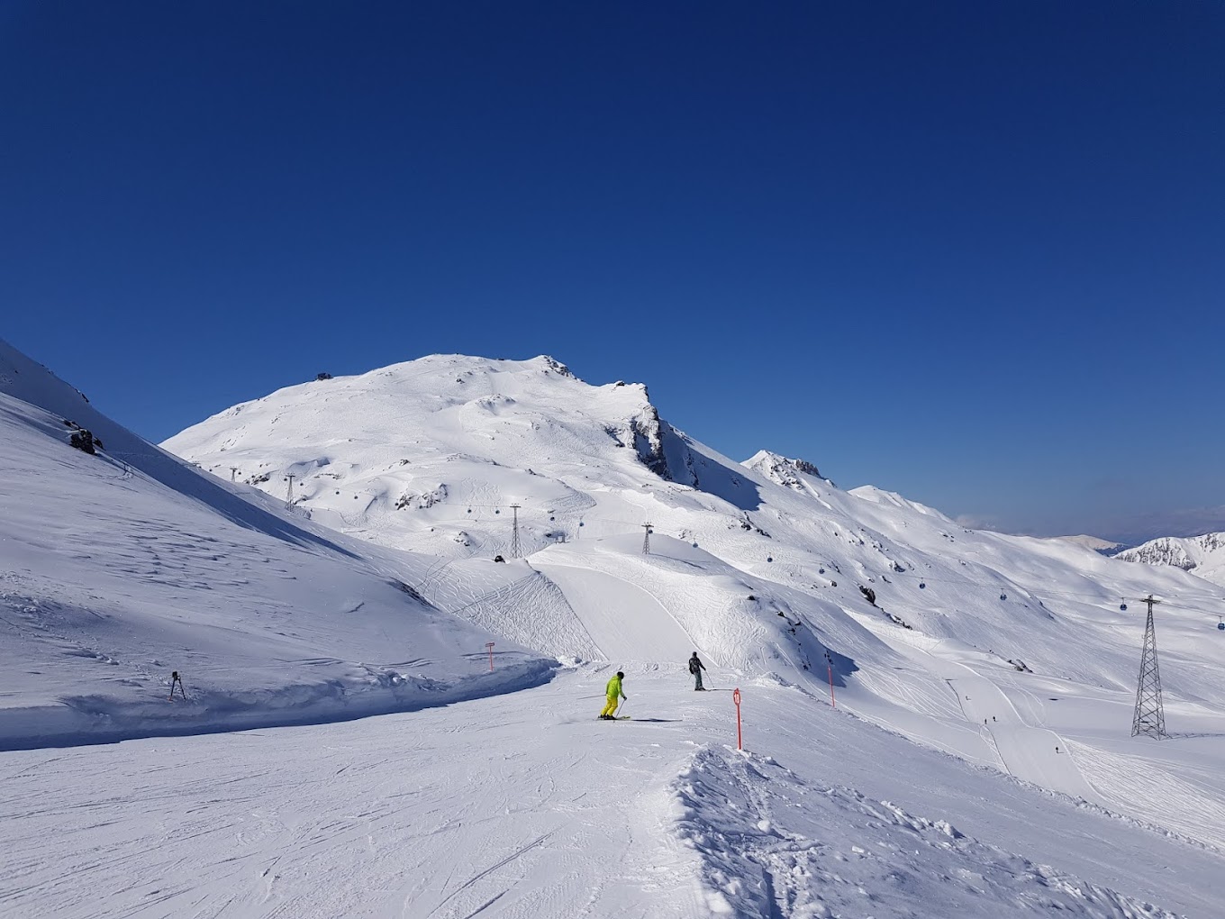 Winter scene at Parsenn ski resort, in Graubünden, Switzerland featuring an active skier descending past a picturesque chalet, set against the backdrop of majestic mountains.
