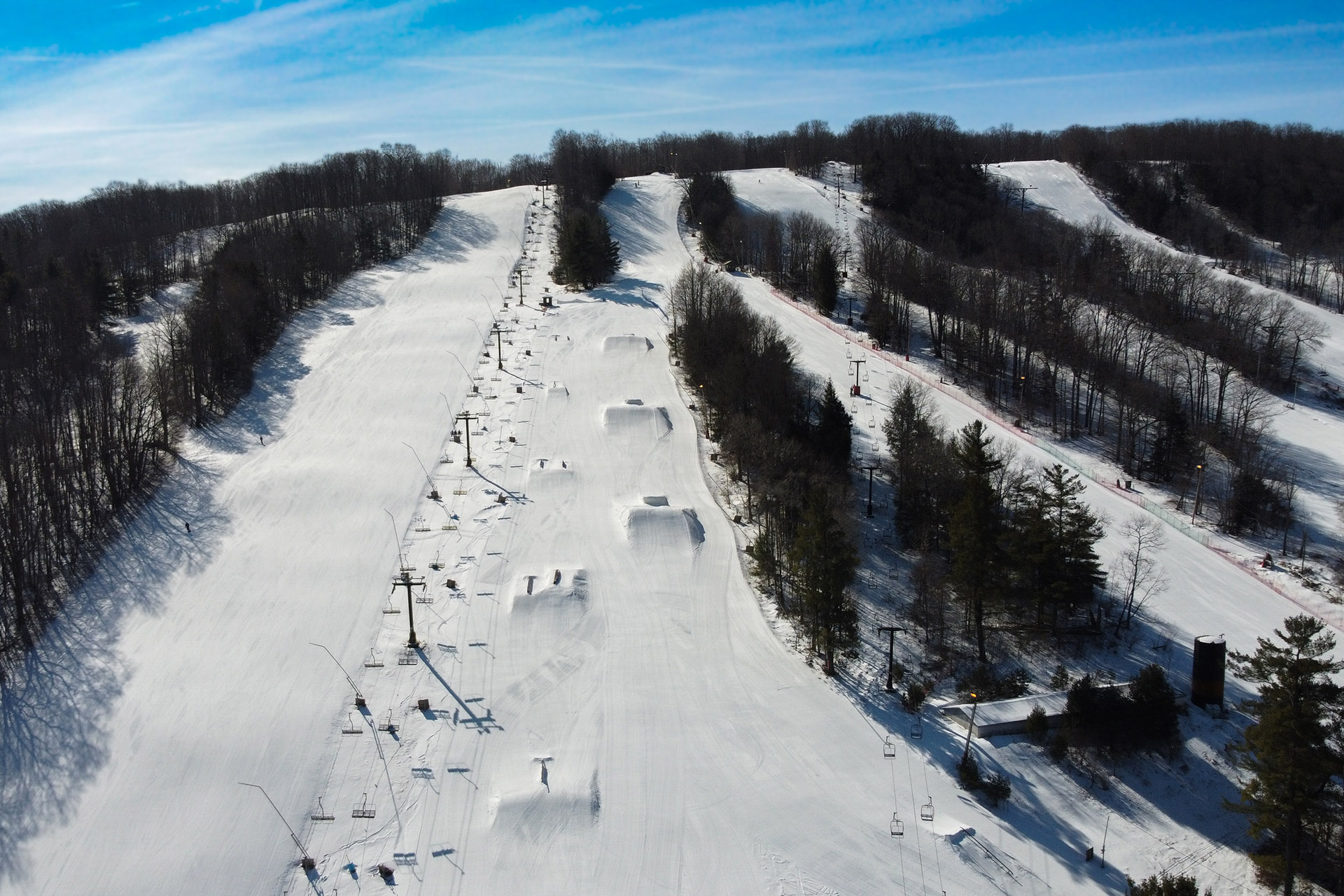 Winter sports scene at Swain Resort in New York, featuring a ski lift traversing the snow-covered slopes of the bustling ski resort.