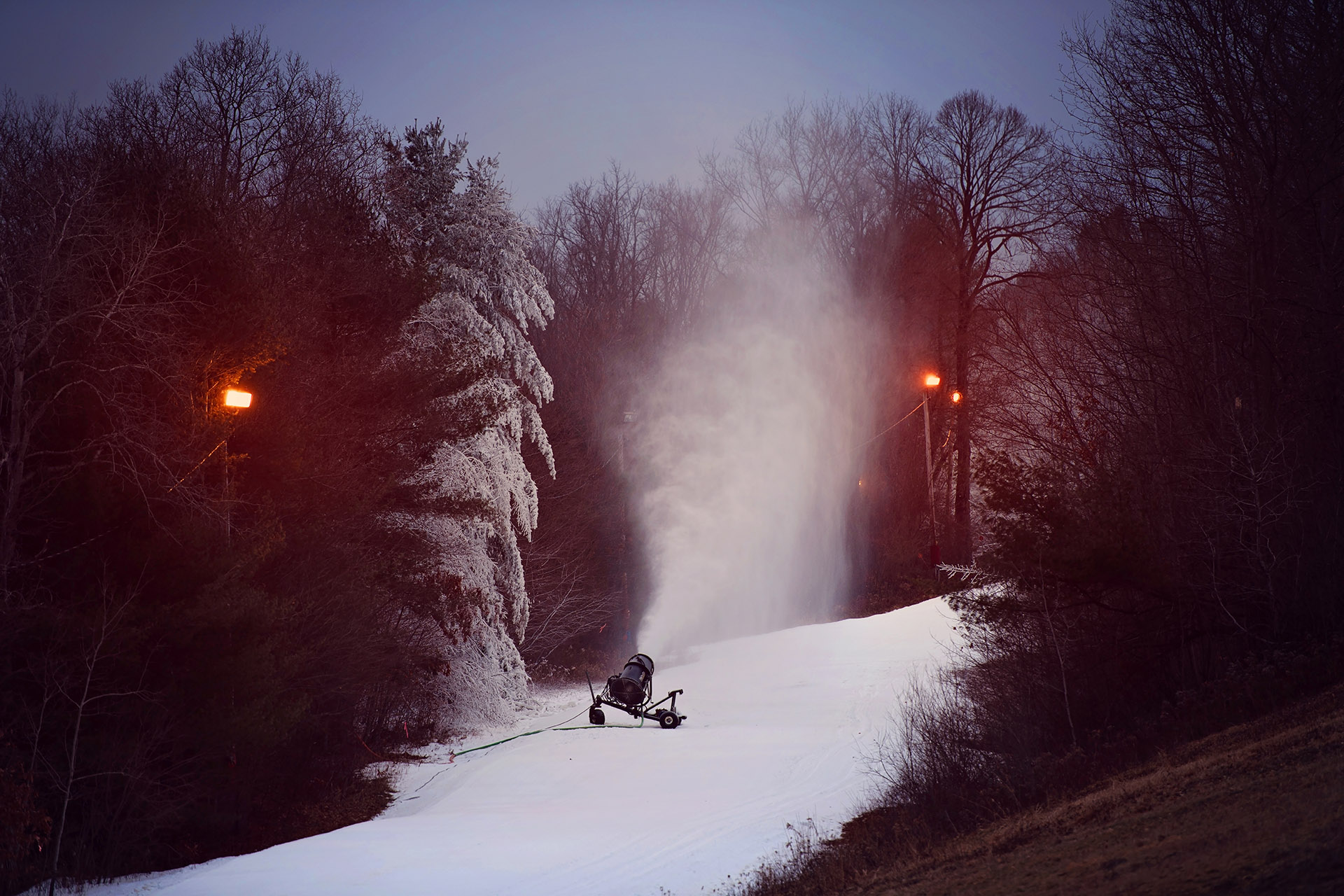 Winter sports scene at Swain Resort in New York, showcasing snowy slopes bustling with skiers. A ski lift can be spotted in the background, as well as a snowmobile parked nearby.