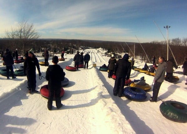 Winter sports enthusiasts enjoying their time at Jack Frost Mountain in White Haven, Pennsylvania, featuring a bustling ski scene complete with skiers, a ski lift, and abundant snow.