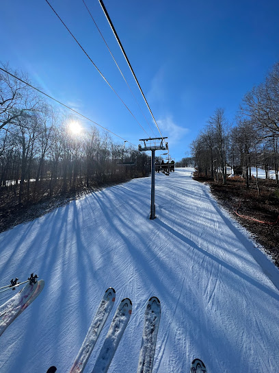 A lively winter sports scene at Jack Frost Mountain Pennsylvania where a skier is descending the slopes. A ski lift is in the foreground creating a quintessential ski resort atmosphere amidst stunning winter scenery.