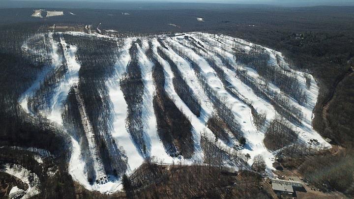 View of Jack Frost Mountain ski resort in White Haven, Pennsylvania, showcasing its snow-covered slopes, ski lift amidst a lively winter sports scene.