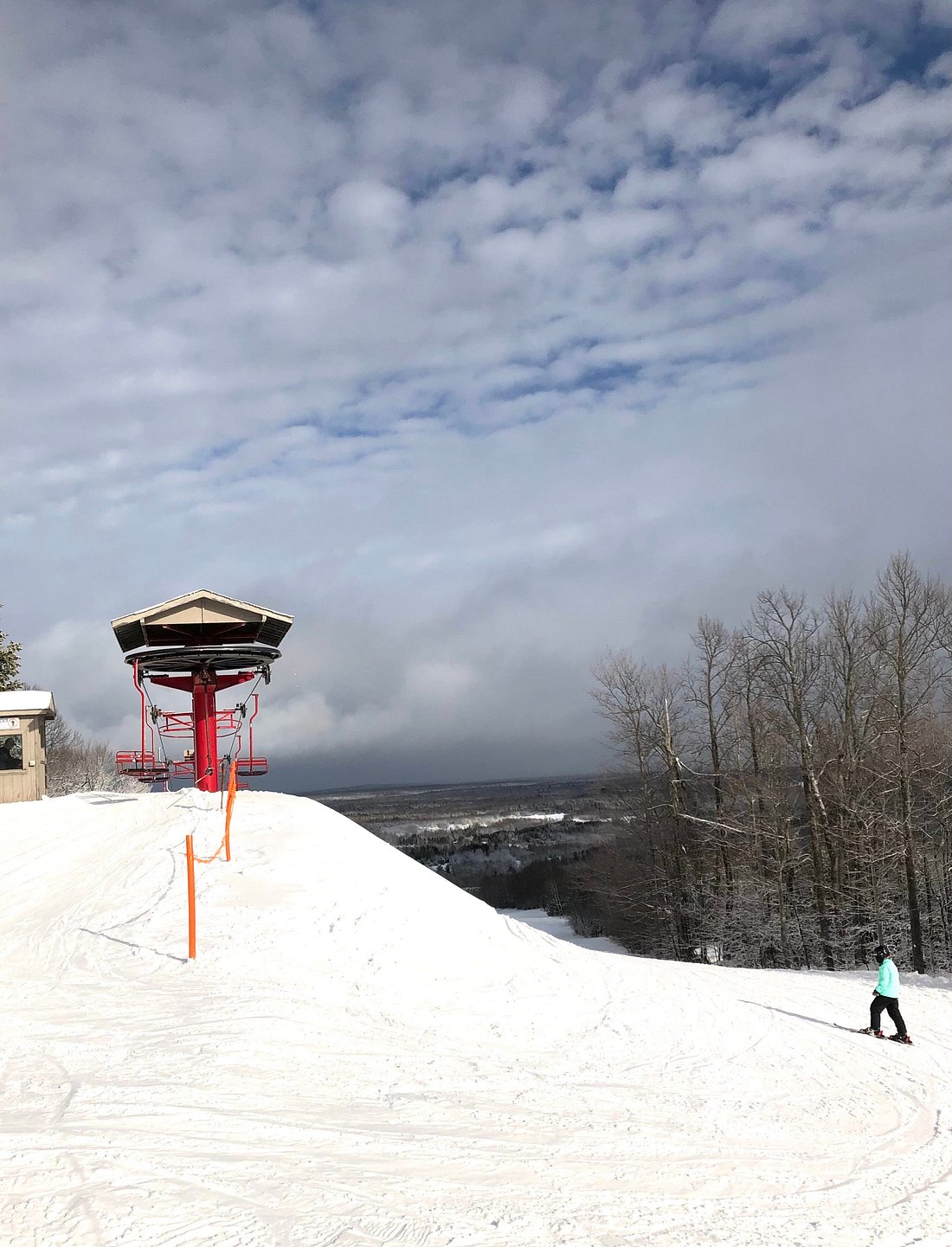 A winter sports scene at Big Powderhorn Mountain ski resort in Bessemer, Michigan, featuring a ski lift, skiers and a stunning winter landscape.