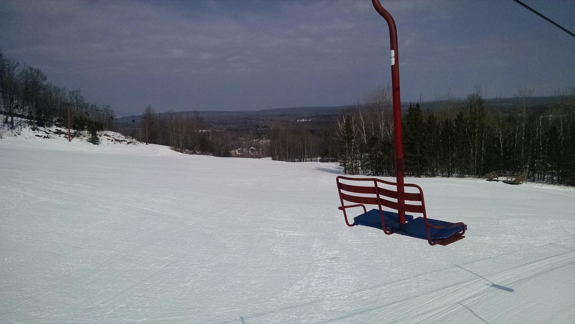 A scenic view at Big Powderhorn Mountain in Bessemer Michigan showcasing a ski lift ascending the snow-covered slopes bustling with skiers enjoying winter sports at the ski resort.