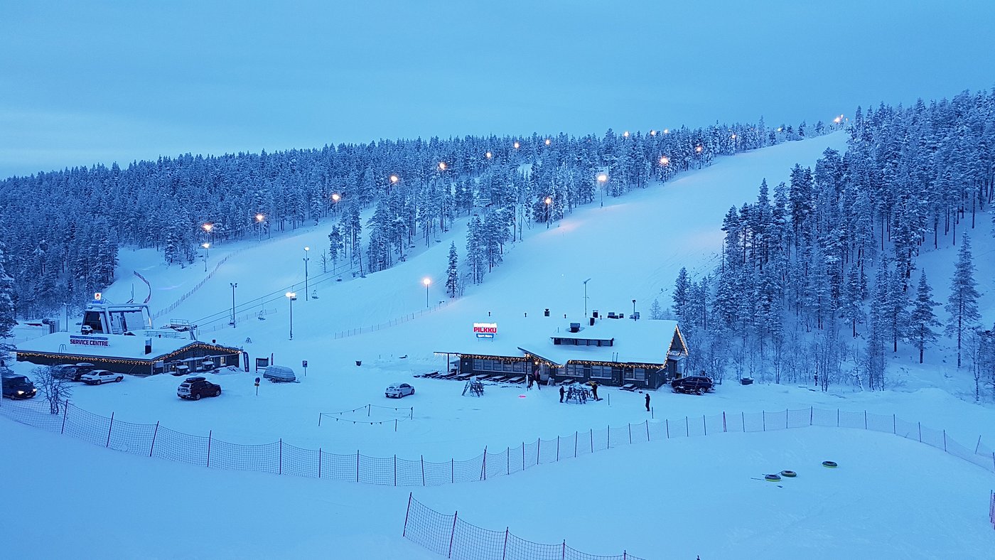 A picturesque winter scene at Saariselkä ski resort in Northern Finland, showcasing stunning scenery filled with snow-covered slopes populated by enthusiasts partaking in various winter sports.