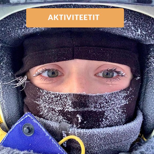 A skier and a snowboarder enjoy a winter sports scene at a chalet in Saariselkä, Northern Finland's winter sports centre, surrounded by the pristine, snow-covered landscape.