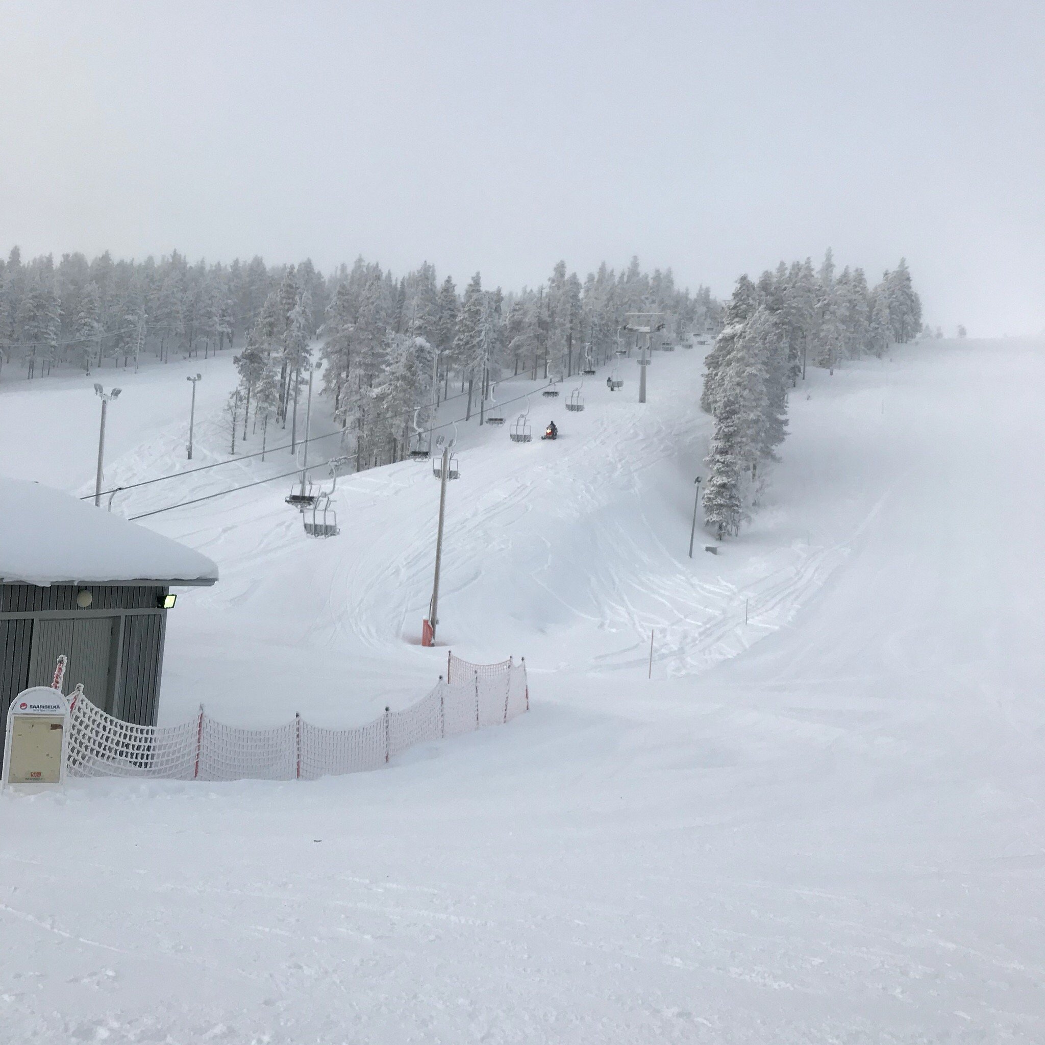 View of the bustling Saariselkä ski resort in Lapland, Finland, featuring a lively winter sports scene on the snow-covered slopes and a ski lift on the backdrop of frosty Finnish scenery.
