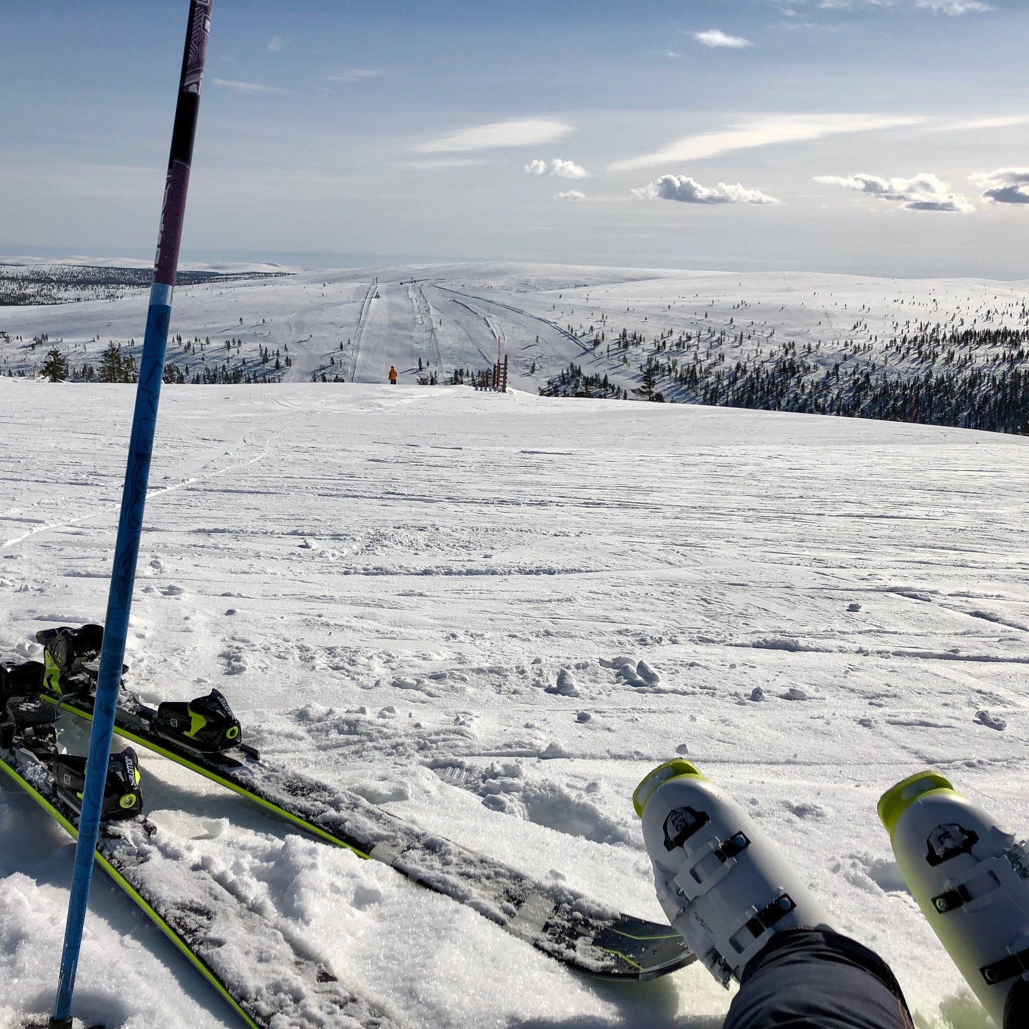 Winter sports scene at Saariselkä in Lapland, Northern Finland, featuring a skier gliding past a chalet amidst a bustling ski resort.