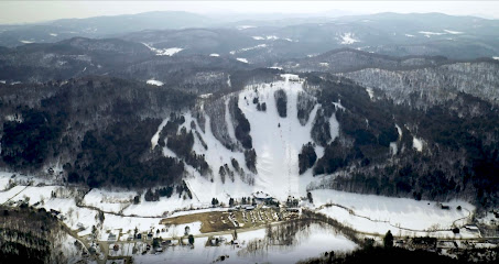 View of Saskadena Six, a bustling ski resort in South Pomfret, Vermont, featuring a winter sports scene with skiers on the slopes and mountain backdrop.