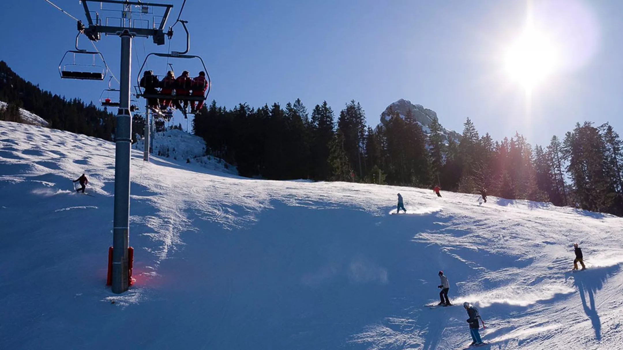Winter sports scene in La Sambuy-Seythenex, France, featuring skiers enjoying the snow-covered slopes, a ski lift traversing the mountain, and a ski resort in the backdrop.