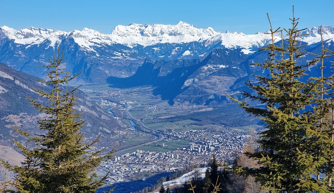 Charming chalet amidst the snow-covered landscape in Feldis Graubünden Switzerland. Mountain peaks faintly visible in the backdrop evoke a sense of serene solitude. Ideal setting for winter sports enthusiasts.