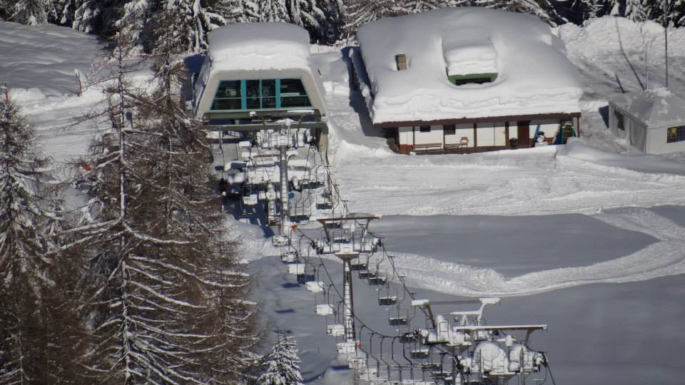 Scenic view of Pescegallo Valgerola in Valtellina, Italy, showcasing its renowned ski resort amidst stunning winter scenery. A chalet and other amenities for winter sports enthusiasts are also visible.