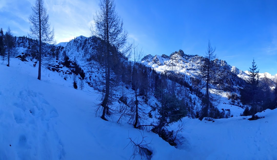 Winter scene at Pescegallo Valgerola in Italy, featuring pristine snow covering slopes bustling with winter sports activities, amidst majestic mountains and a cozy chalet.