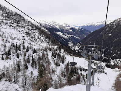 A ski resort in Pescegallo Valgerola, Italy, featuring a ski lift, a challet and a bustling winter sports scene.