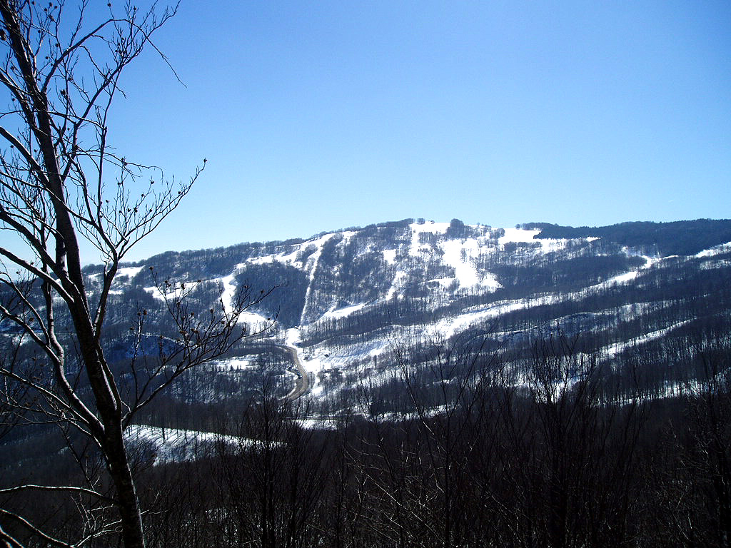View of the Schia - Monte Caio ski resort in Emilia-Romagna, Italy, with mountains in the backdrop. A chalet peeks beneath the winter sports scene imbued with an overall stunning winter scenery.