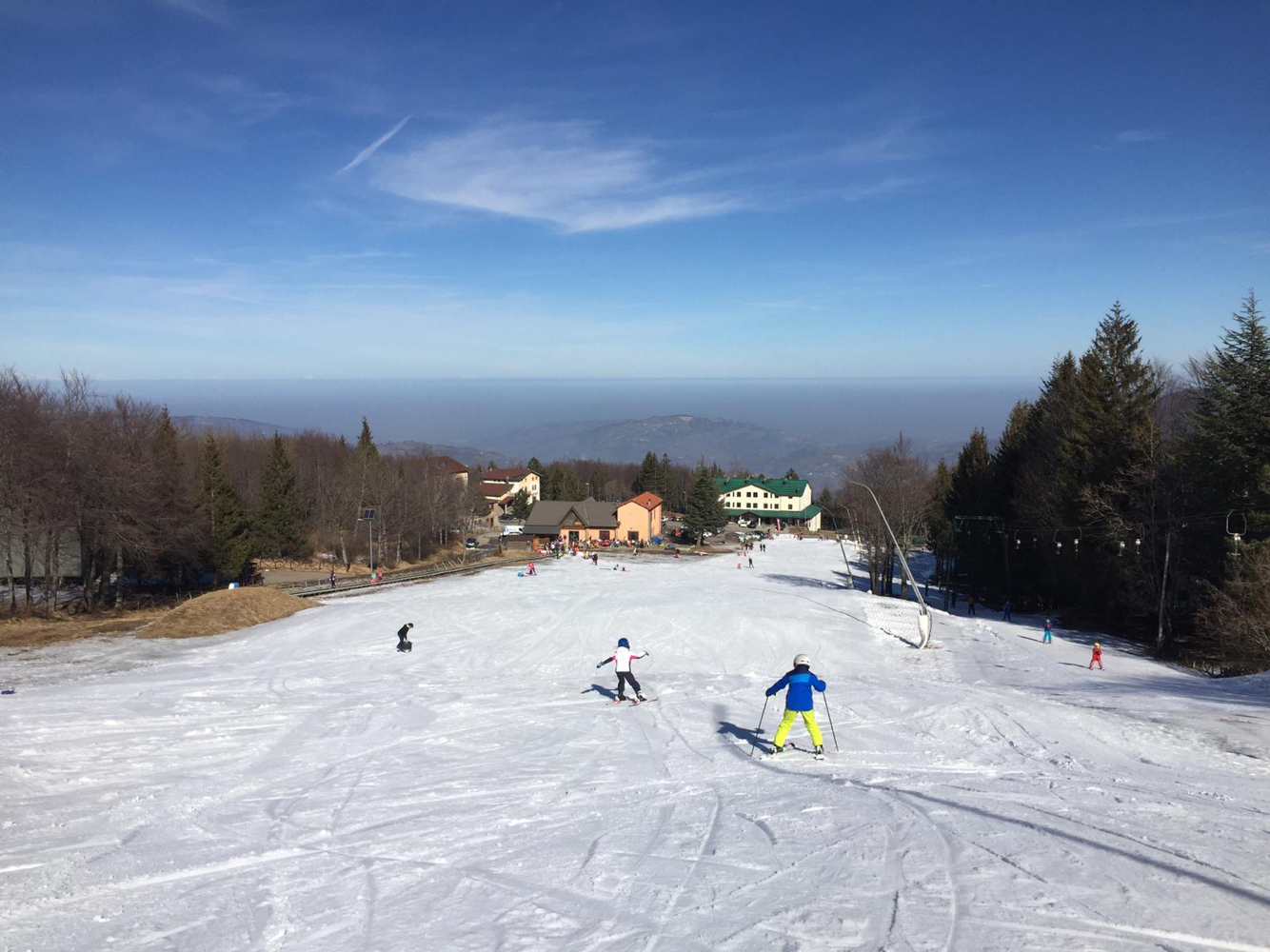 Skiers enjoying a winter sports scene at Schia - Monte Caio a ski resort in Parma Italy showcasing a challet and other amenities of a winter sports centre.