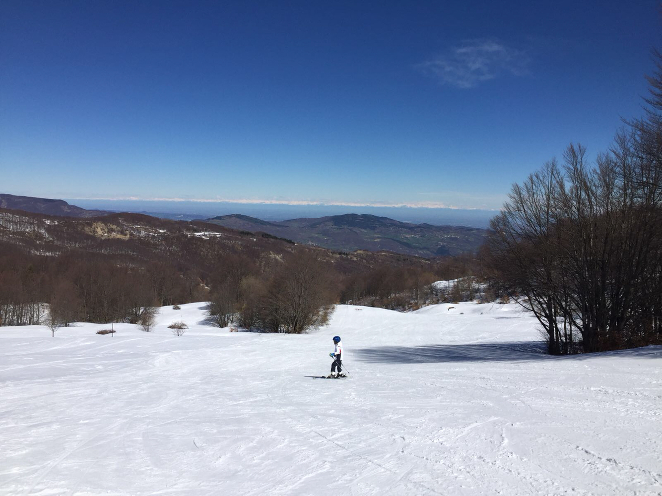 A skier enjoying a winter sports scene at the Schia – Monte Caio ski resort in Parma, Italy, with a charming chalet and ski lift in the backdrop.