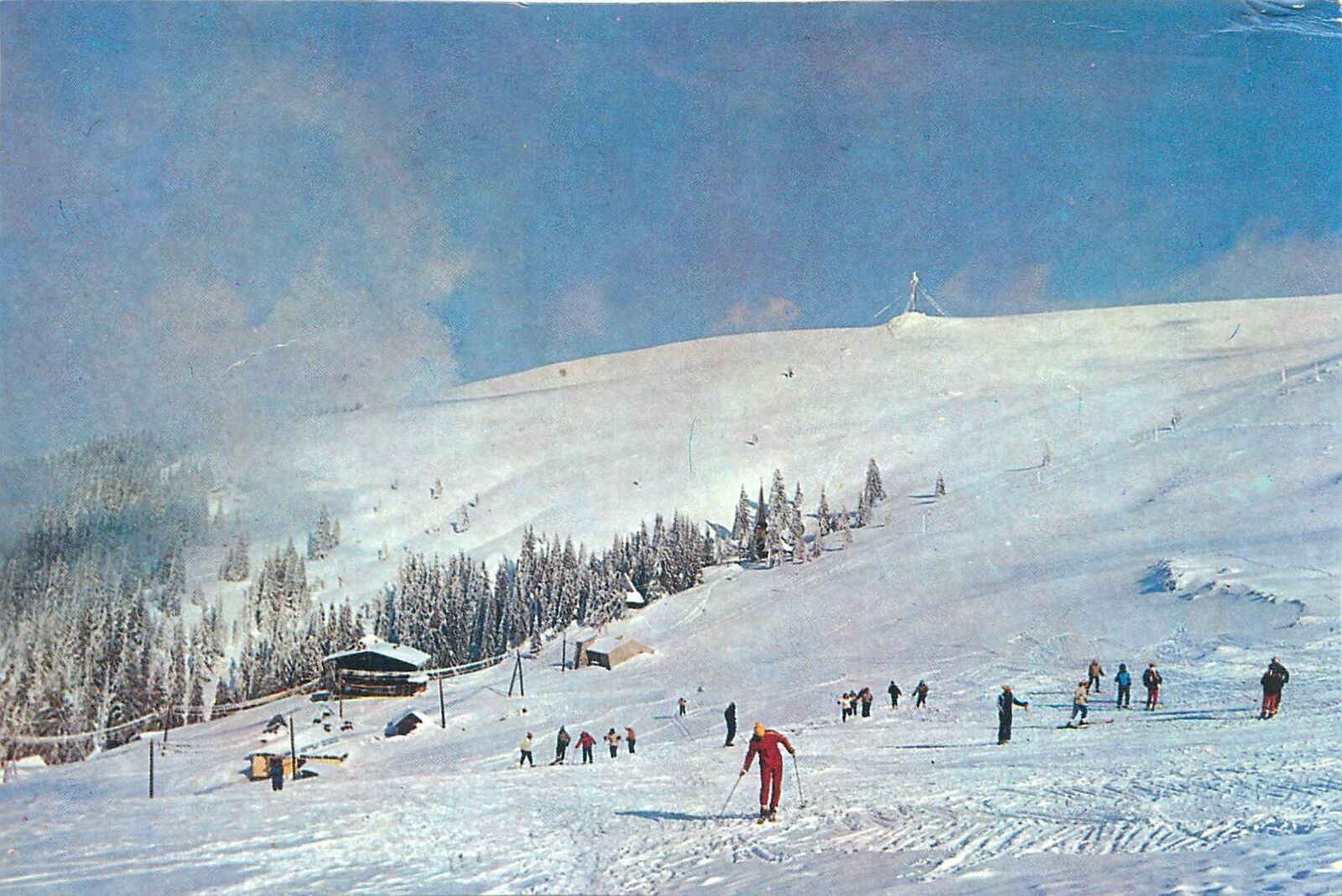 Muntele Mic in Romania - a group of people skiing down a snow covered mountain.