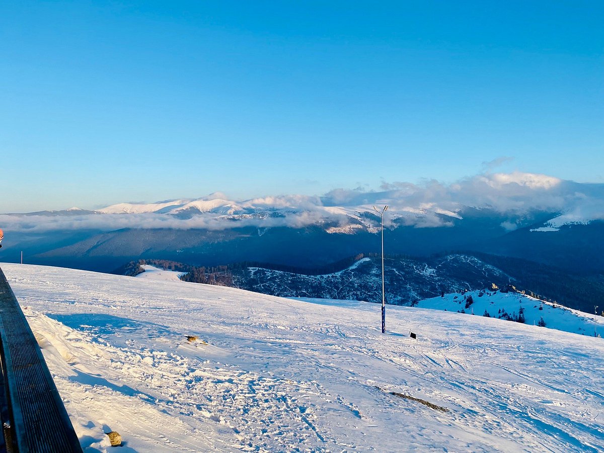 Muntele Mic in Romania - a person standing on top of a snow covered mountain.