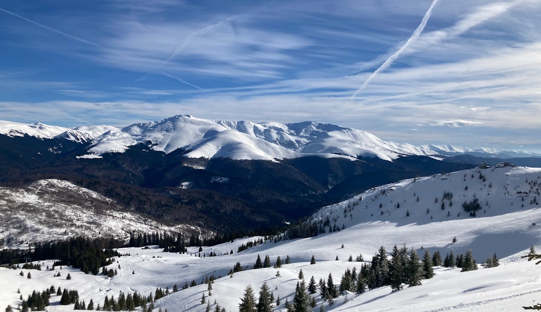 View of Muntele Mic featuring a chalet and a bustling ski resort. Winter sports enthusiasts enjoy snow-covered slopes set against a beautiful mountain backdrop.