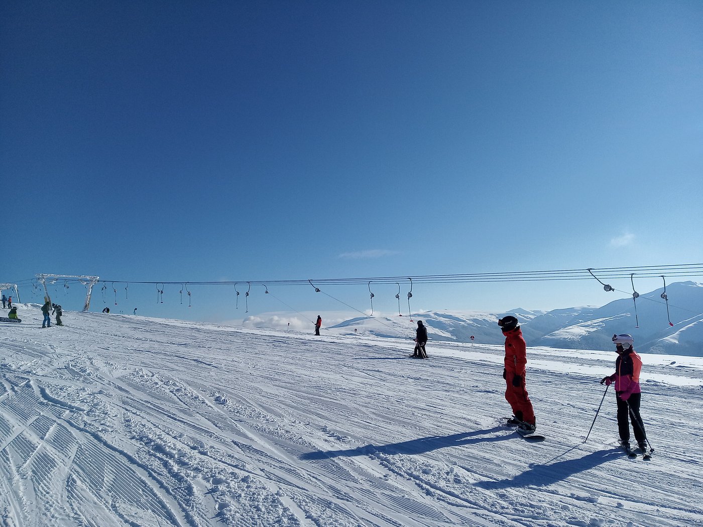 A skier enjoying the slopes at Muntele Mic ski resort in Romania, with a ski lift visible in the background amidst a beautiful winter sports scene.