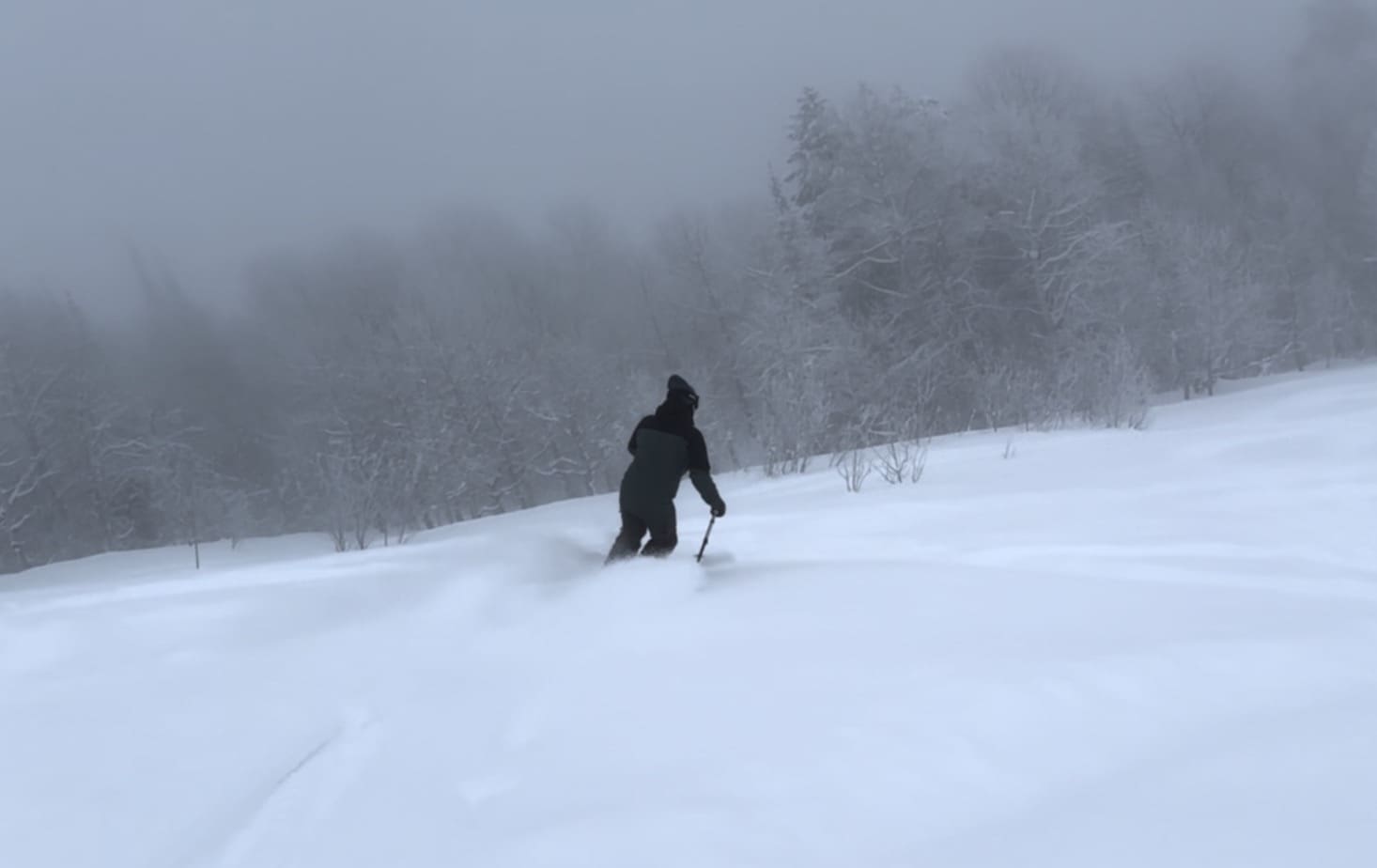 A skier making their way down the slopes at Magic Mountain Resort in Kimberly, Idaho, with a picturesque winter scenery in the background.