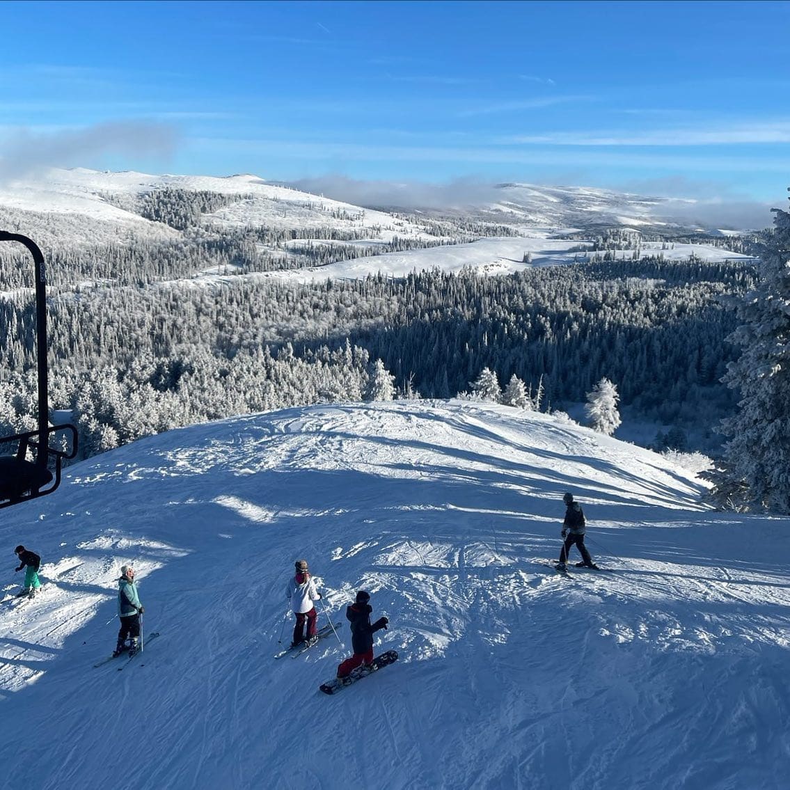 Winter sports enthusiasts enjoying the slopes at Magic Mountain Resort, Idaho, with the ski lift in operation, skiing is the main activity observed.