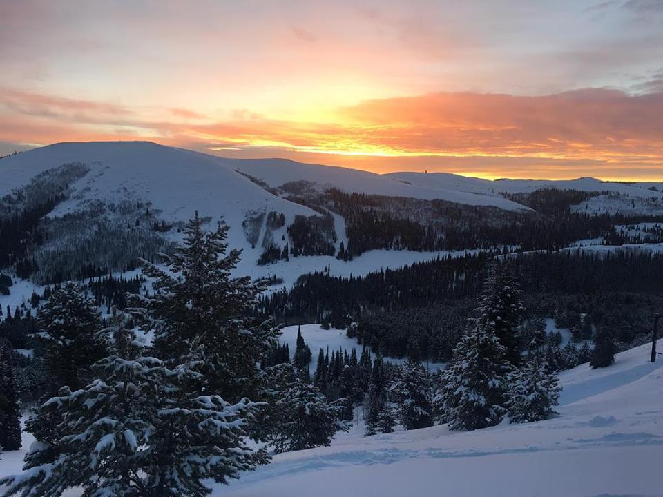 View of the picturesque Magic Mountain Resort in Kimberly, Idaho, showcasing the bustling winter sports scene amidst a stunning snow-covered landscape, including a charming chalet and a busy ski resort.