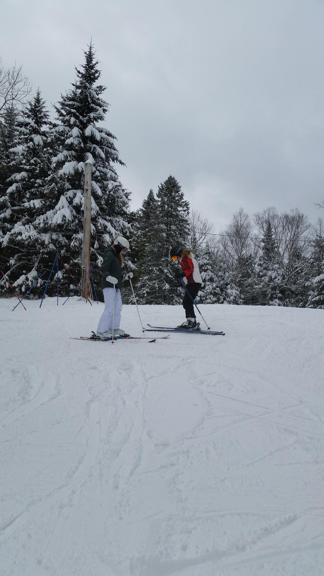 A winter sports scene at Vallée Bleue Laurentides Quebec showcasing a skier skillfully navigating the snowy slopes with a ski lift and others enjoying their day in the background.