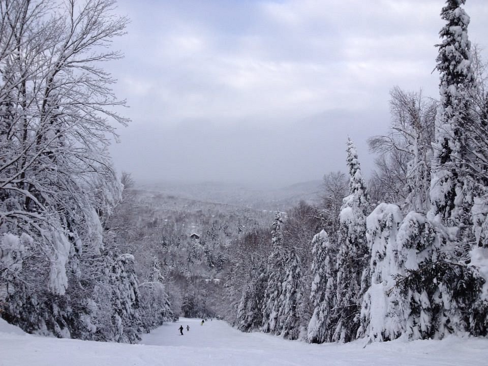 Winter sports scene at Vallée Bleue in Val-David, Quebec, showcasing stunning landscape covered in snow. Visible ski resort and sports centre amidst scenic backdrop.