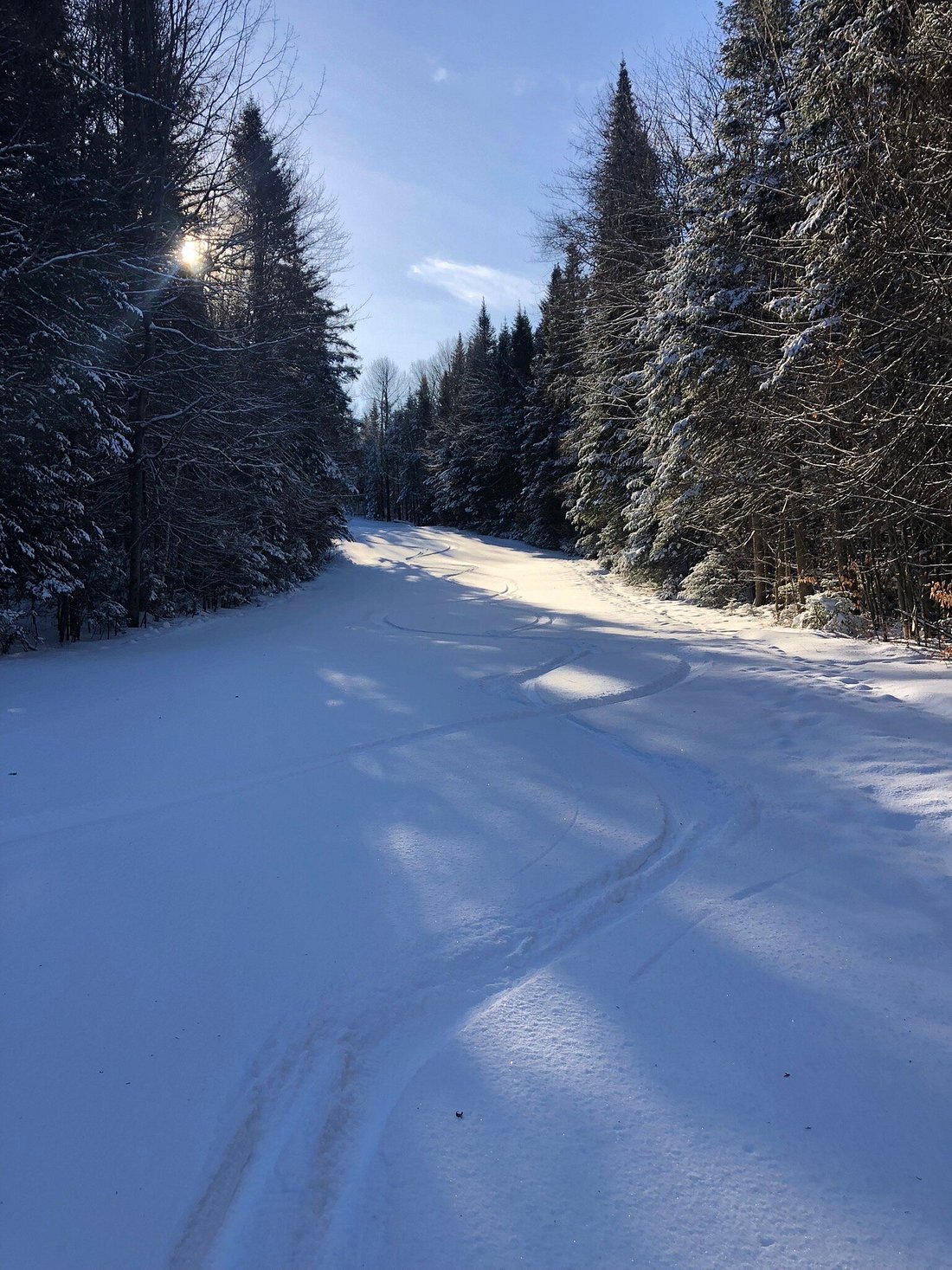 Winter sports scene at Vallée Bleue, Quebec, featuring a chalet surrounded by stunning snowy landscape, and a snowmobile parked near by.