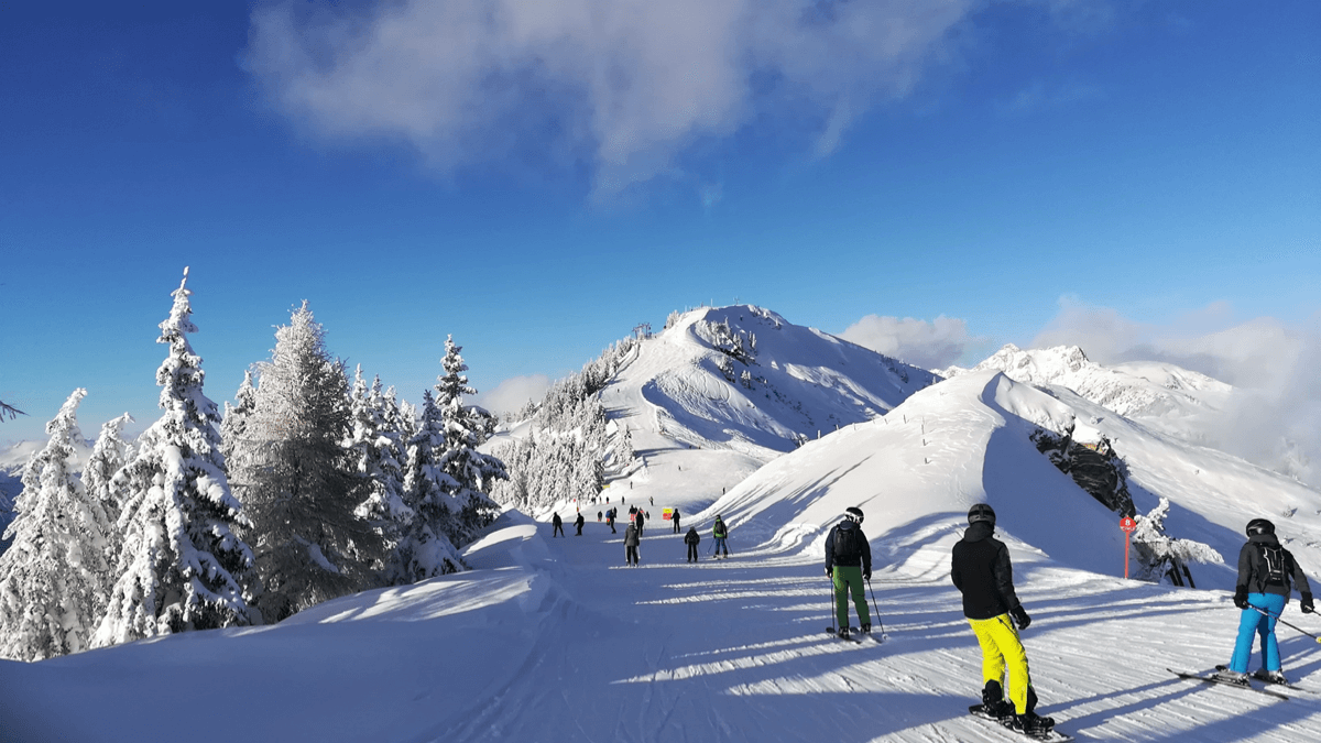 Großarltal | ​Dorfgastein in Austria - a group of people skiing down a snowy mountain.