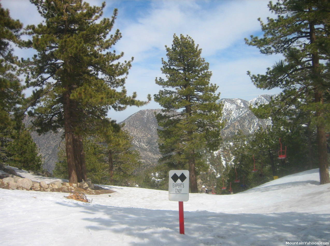 A skier is enjoying a bright winter day at Mt Waterman ski resort in California USA. The ski lift is gently rolling in the backdrop against the backdrop of a picturesque mountain.