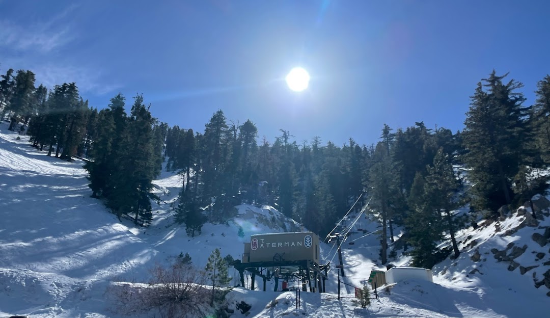 Winter sports scene at the Mt. Waterman ski resort in Pearblossom, California featuring a ski lift amidst stunning winter scenery.
