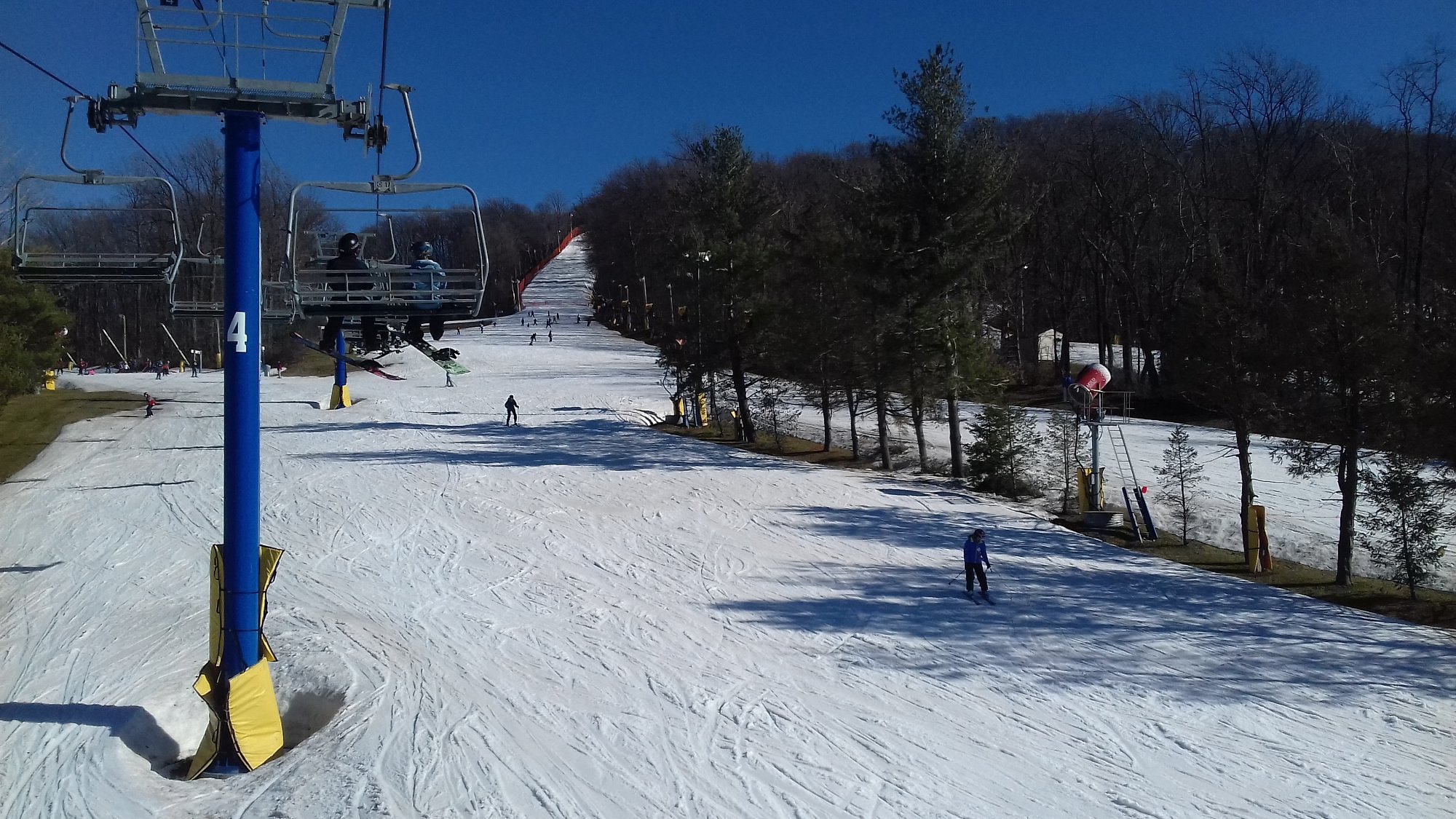 Winter sports scene at Liberty Mountain, Fairfield Pennsylvania, featuring a ski resort with ski lift and snow-covered slopes, including a skier enjoying the terrain.